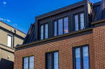 Experience modern urban living in this stunning multi-story residence featuring a striking brick facade and a sleek black metal roof.