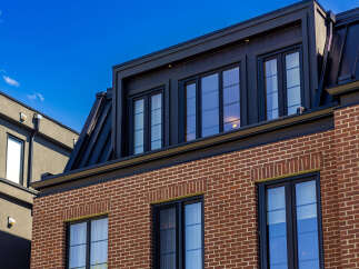 Experience modern urban living in this stunning multi-story residence featuring a striking brick facade and a sleek black metal roof.
