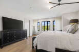 Experience luxury in this master bedroom, featuring a large black dresser topped with a sleek flat-screen TV.