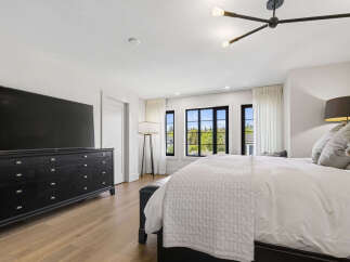 Experience luxury in this master bedroom, featuring a large black dresser topped with a sleek flat-screen TV.