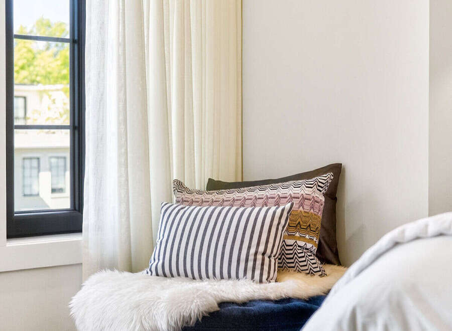 Experience ultimate comfort in this cozy reading nook, featuring a plush navy ottoman adorned with a luxurious white sheepskin throw.