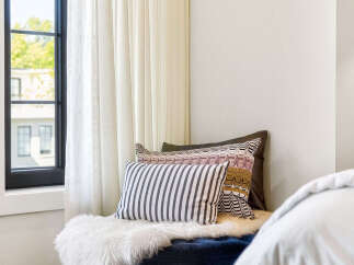 Experience ultimate comfort in this cozy reading nook, featuring a plush navy ottoman adorned with a luxurious white sheepskin throw.