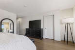 Experience modern comfort in this spacious bedroom, featuring a sleek black dresser topped with a large flat-screen TV and a striking arched mirror.