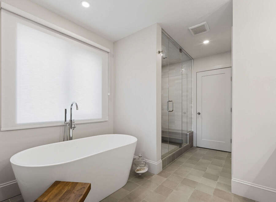 Experience luxury in this modern bathroom featuring a freestanding soaking tub with a sleek chrome faucet, perfect for unwinding.