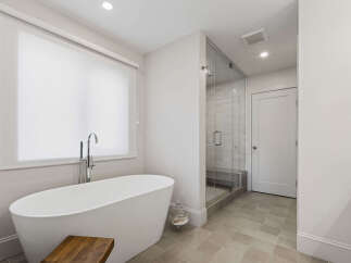 Experience luxury in this modern bathroom featuring a freestanding soaking tub with a sleek chrome faucet, perfect for unwinding.