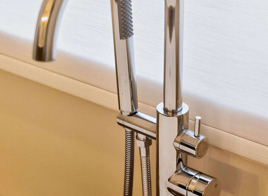 Experience luxury bathing with this modern freestanding bathtub faucet, featuring a sleek chrome finish and an integrated handheld showerhead.