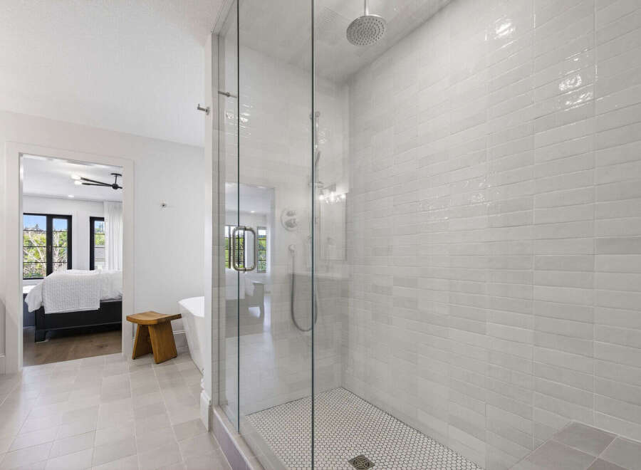 Experience modern luxury in this stunning bathroom featuring a spacious glass-enclosed shower with sleek white subway tile and a refreshing rain showerhead.