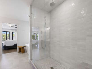 Experience modern luxury in this stunning bathroom featuring a spacious glass-enclosed shower with sleek white subway tile and a refreshing rain showerhead.
