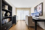 This home office features a sleek black bookshelf filled with decor and books, complemented by a modern black dresser.