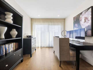 This home office features a sleek black bookshelf filled with decor and books, complemented by a modern black dresser.