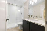 This modern bathroom features a sleek glass-enclosed shower with white subway tiles and a rainfall showerhead.
