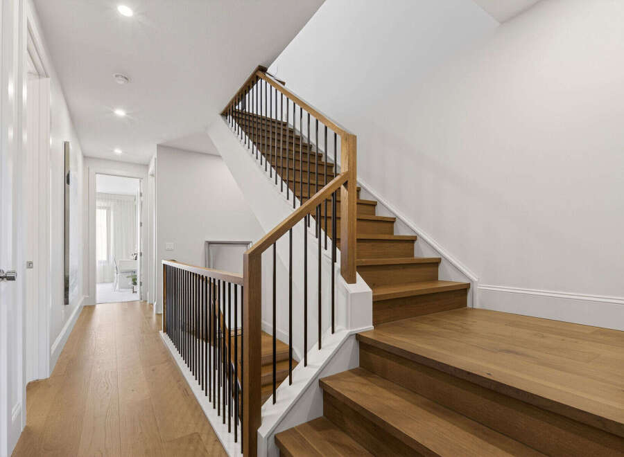 Ascend to the upper level via a beautifully crafted wooden staircase, featuring a modern black metal railing.