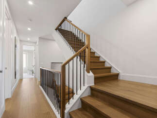 Ascend to the upper level via a beautifully crafted wooden staircase, featuring a modern black metal railing.
