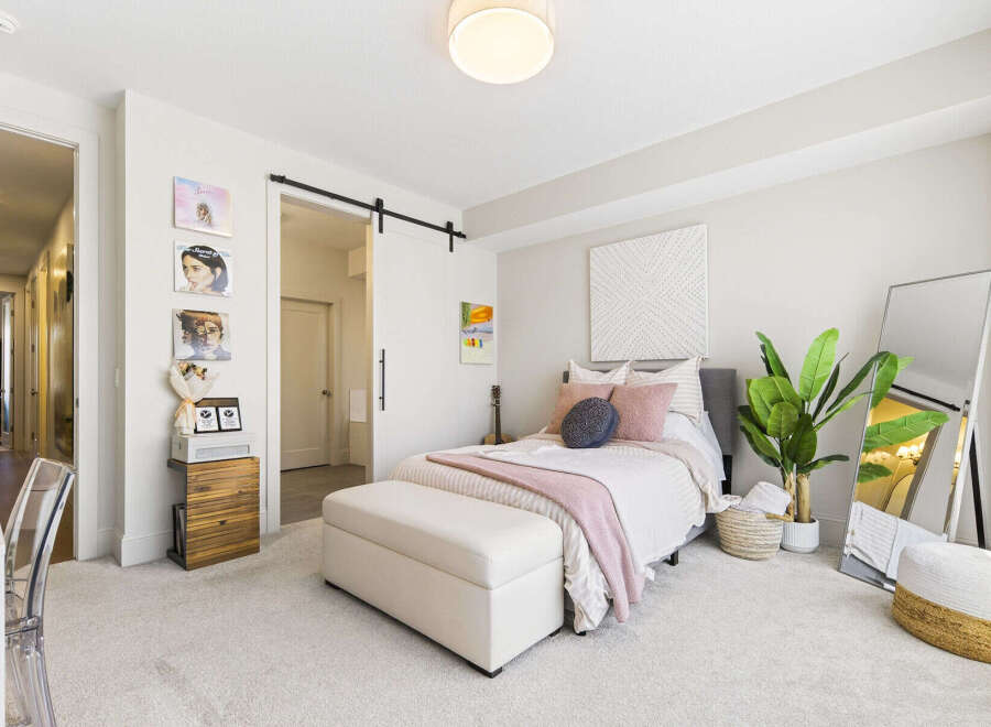 This charming bedroom features a cozy queen-size bed adorned with plush pink and navy pillows, complemented by a soft pink throw blanket.