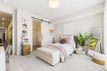 This charming bedroom features a cozy queen-size bed adorned with plush pink and navy pillows, complemented by a soft pink throw blanket.