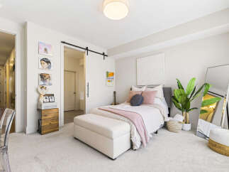 This charming bedroom features a cozy queen-size bed adorned with plush pink and navy pillows, complemented by a soft pink throw blanket.