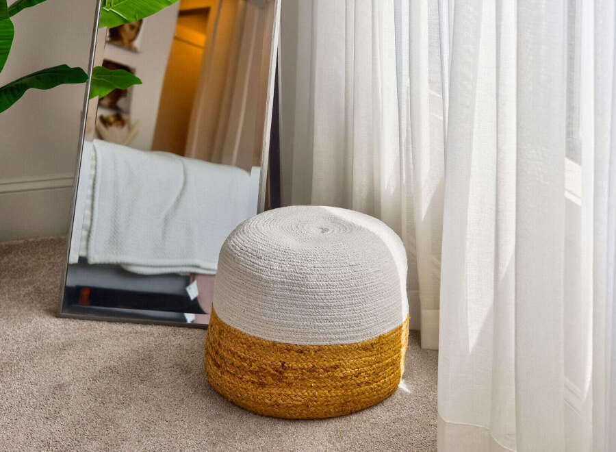 Enhance your living space with this charming, two-toned woven ottoman, featuring a natural jute base and a soft white top.