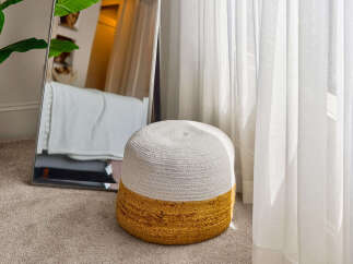 Enhance your living space with this charming, two-toned woven ottoman, featuring a natural jute base and a soft white top.