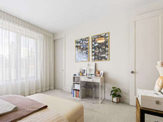 Bright and airy bedroom featuring sheer white curtains that allow natural light to flood the space.
