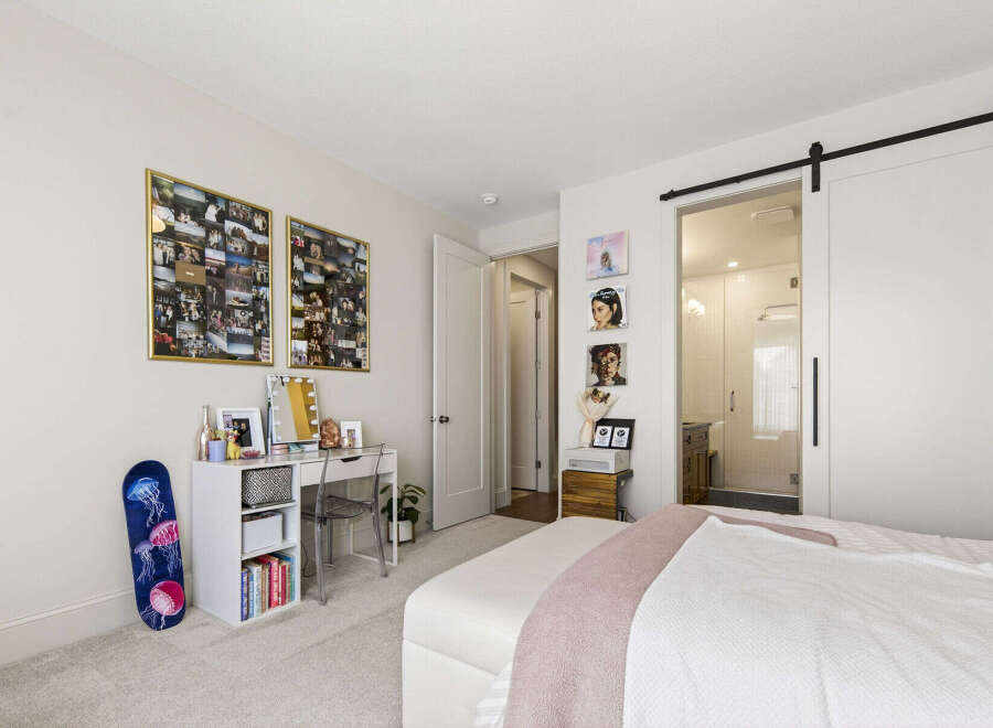 Discover this charming bedroom featuring a stylish white desk with a clear acrylic chair, perfect for a home office or vanity area.