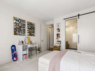 Discover this charming bedroom featuring a stylish white desk with a clear acrylic chair, perfect for a home office or vanity area.