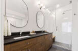 Experience modern luxury in this stunning bathroom featuring a spacious double vanity with sleek black countertops and warm wood cabinetry.