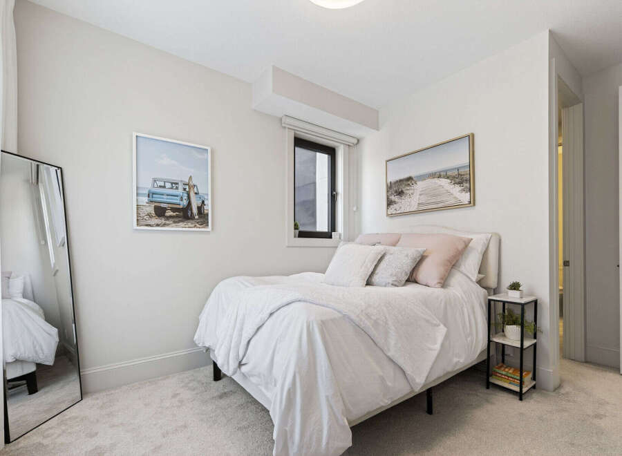 This charming bedroom features a comfortable queen-size bed adorned with crisp white linens and plush decorative pillows.