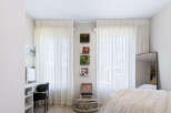 This bright and airy bedroom features sheer white curtains that allow natural light to flood the space.