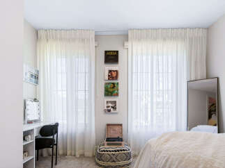 This bright and airy bedroom features sheer white curtains that allow natural light to flood the space.
