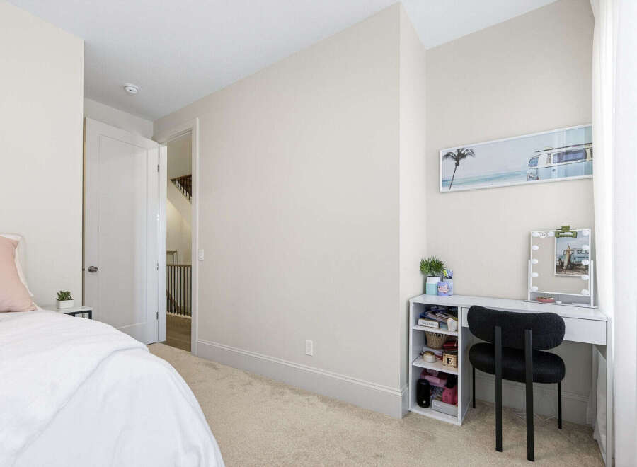 This bright and airy bedroom features a comfortable bed with plush pillows and a white duvet, perfect for relaxation.