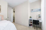This bright and airy bedroom features a comfortable bed with plush pillows and a white duvet, perfect for relaxation.