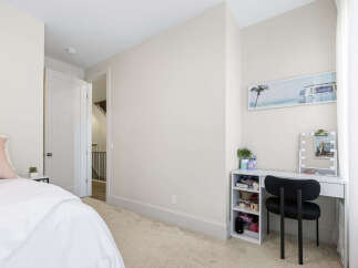 This bright and airy bedroom features a comfortable bed with plush pillows and a white duvet, perfect for relaxation.