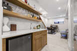 This modern basement features a stylish wet bar with a built-in mini-fridge and ample shelving for glassware and spirits.