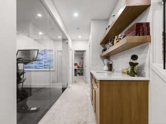 This modern home features a stylish wet bar with floating wooden shelves, a sleek white countertop, and a contemporary sink, perfect for entertaining.
