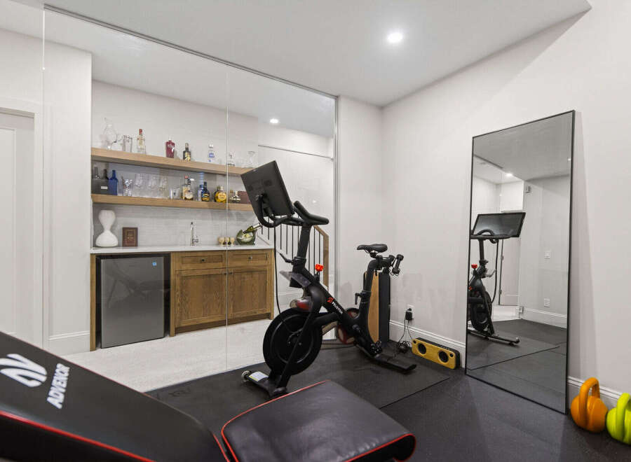 This modern home gym features a Peloton bike and a weight bench, perfect for your fitness routine.