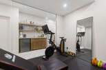 This modern home gym features a Peloton bike and a weight bench, perfect for your fitness routine.
