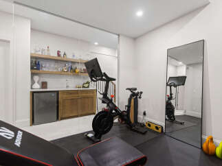 This modern home gym features a Peloton bike and a weight bench, perfect for your fitness routine.