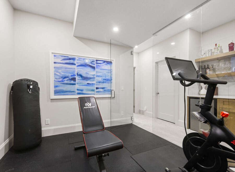 This home gym features a Peloton bike, a punching bag, and a weight bench, perfect for a comprehensive workout.