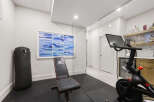 This home gym features a Peloton bike, a punching bag, and a weight bench, perfect for a comprehensive workout.