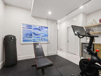 This home gym features a Peloton bike, a punching bag, and a weight bench, perfect for a comprehensive workout.