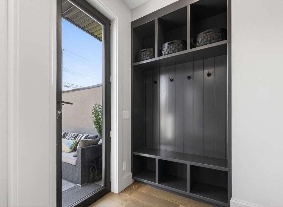 This entryway features a stylish dark gray built-in storage unit with open shelving and hooks, perfect for organizing coats and accessories.