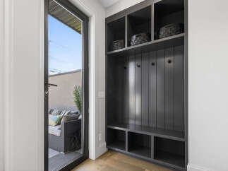 This entryway features a stylish dark gray built-in storage unit with open shelving and hooks, perfect for organizing coats and accessories.