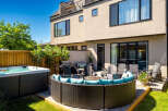 Enjoy outdoor living at its finest with this luxurious backyard oasis, featuring a relaxing hot tub and a spacious, modern patio area.