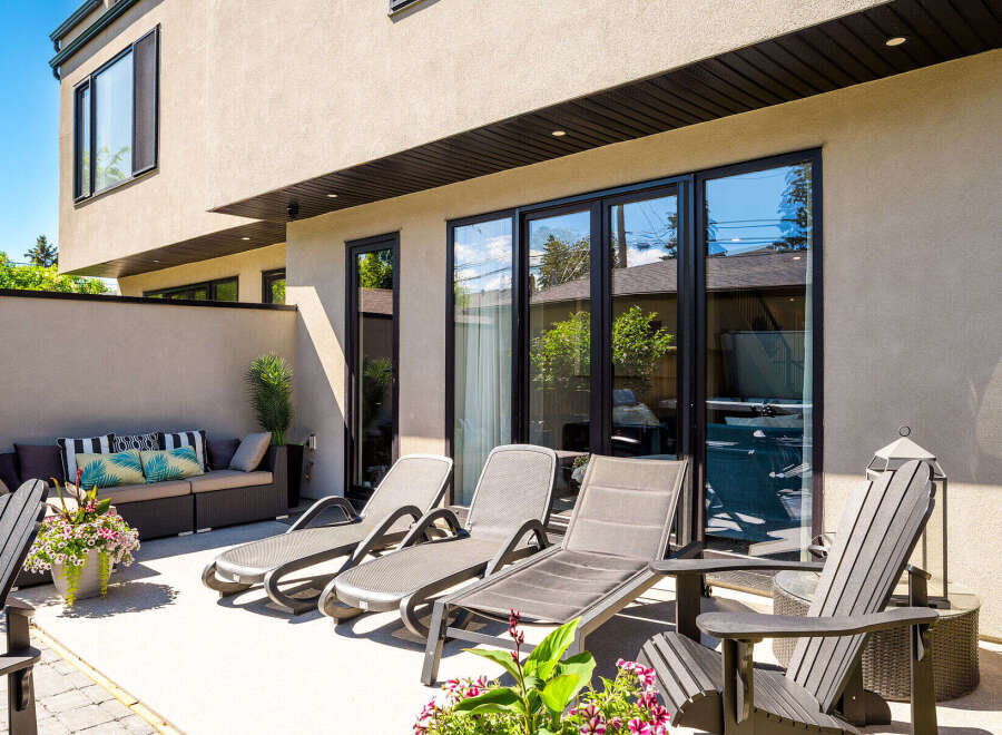 Enjoy outdoor living at its finest on this spacious patio, featuring comfortable lounge chairs and a stylish outdoor sofa perfect for relaxation.
