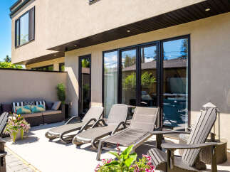 Enjoy outdoor living at its finest on this spacious patio, featuring comfortable lounge chairs and a stylish outdoor sofa perfect for relaxation.