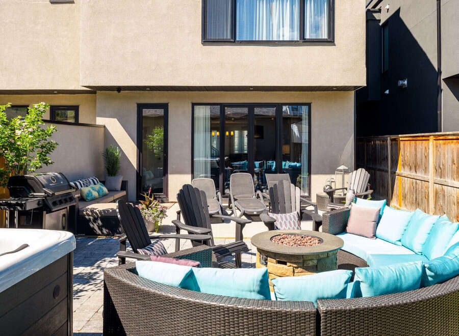 Enjoy outdoor living at its finest with this stunning patio featuring a luxurious sectional sofa, a cozy fire pit, and a premium gas grill.