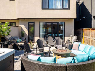 Enjoy outdoor living at its finest with this stunning patio featuring a luxurious sectional sofa, a cozy fire pit, and a premium gas grill.