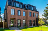 Discover modern luxury in this stunning brick townhouse featuring a sleek black metal roof and expansive windows.