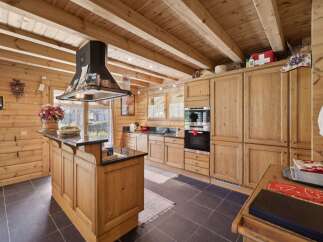 Experience rustic charm in this beautifully appointed log cabin kitchen, featuring warm wooden cabinetry and exposed beams.