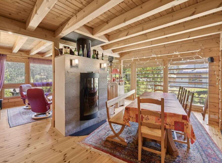 Experience rustic charm in this inviting dining area, featuring a cozy fireplace and a large wooden dining table perfect for family gatherings.
